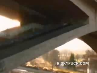 Pair of sluts sucking pecker in an empty but still public place